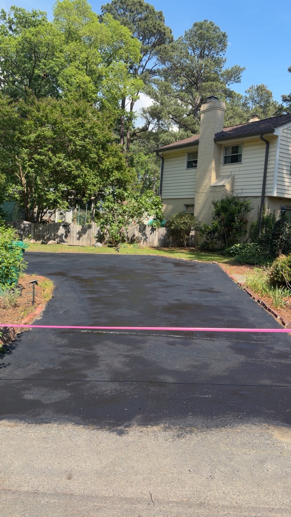 Same driveway after seal coating — fresh black asphalt with crisp edges