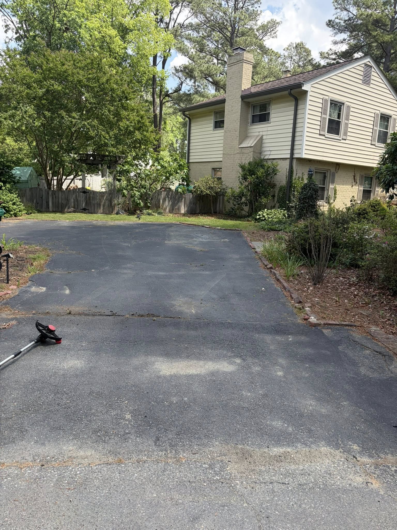 Driveway before seal coating — faded gray asphalt with hairline cracks