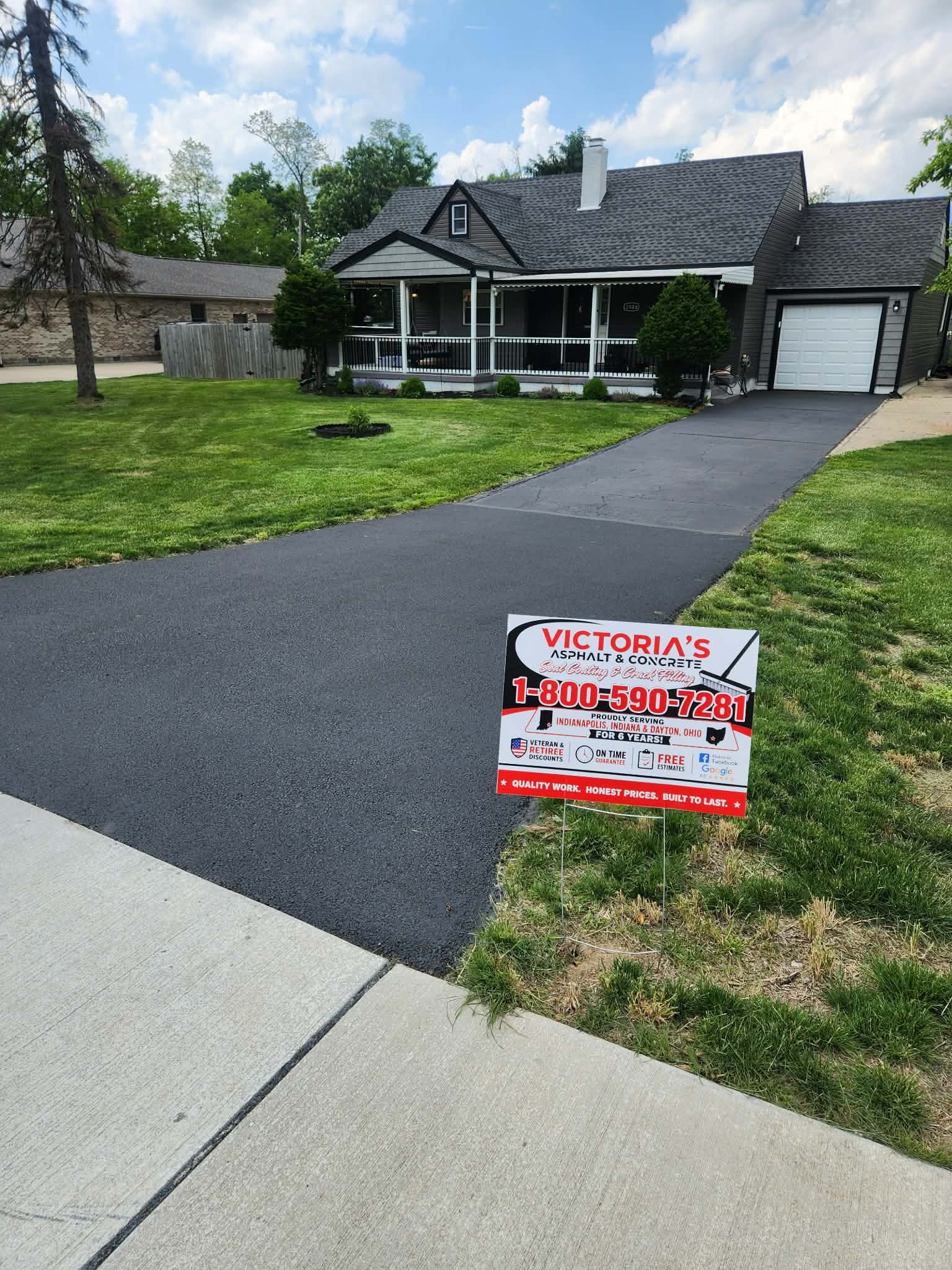 Freshly sealed driveway with Victoria's Asphalt & Concrete yard sign