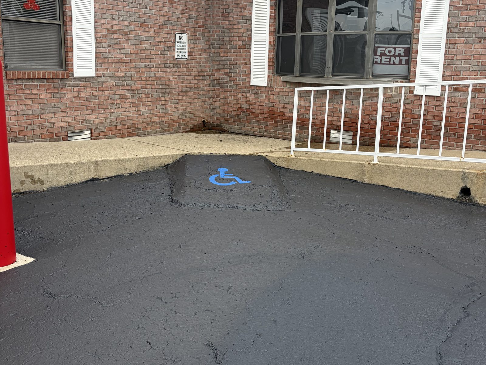 Freshly sealed commercial parking lot with a newly painted blue ADA accessible stall marking