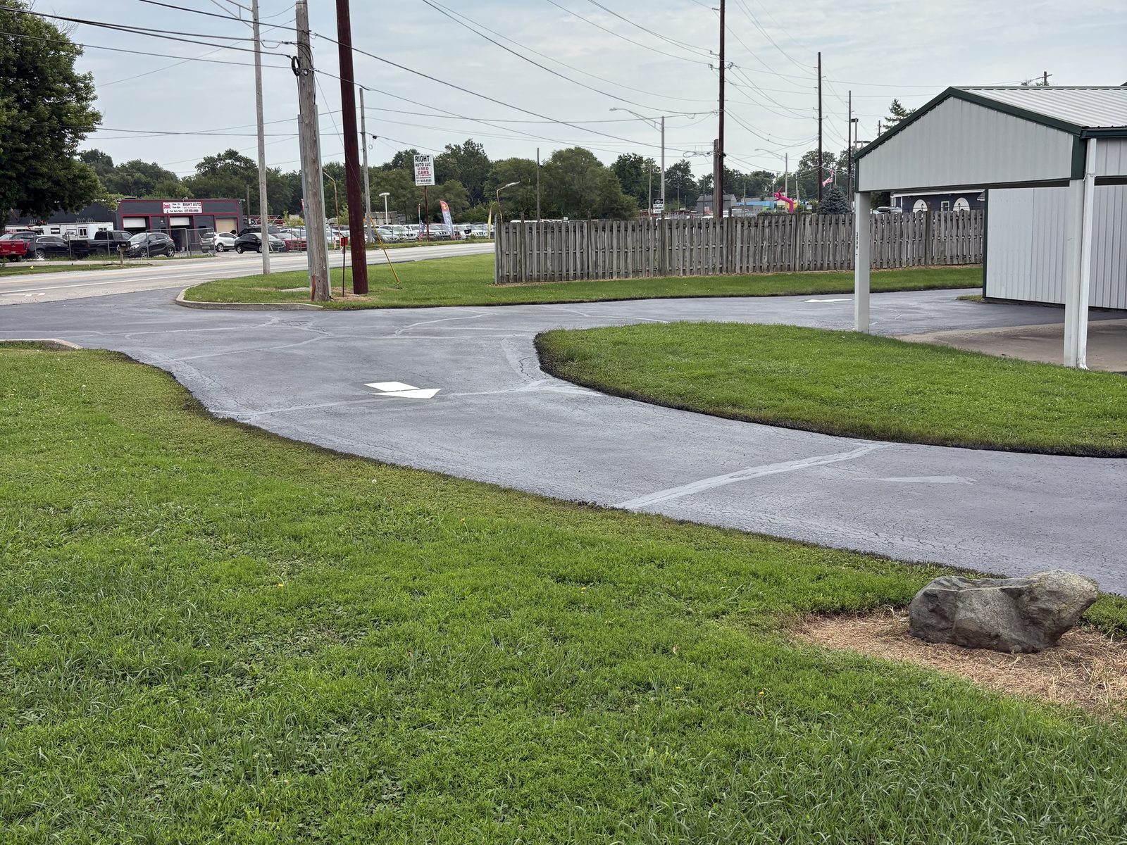 Long sealed commercial access lane curving between grass shoulders